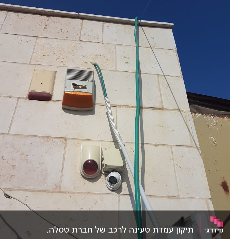 מערכת אזעקה עם חוטים ירוקים על קיר חיצוני